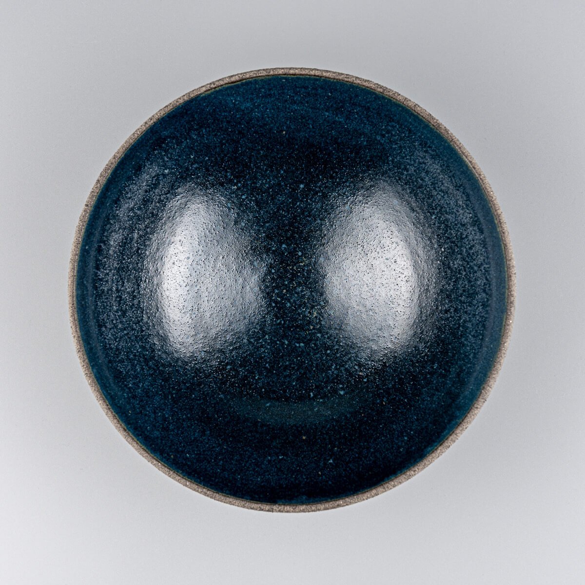 Top-down view of handmade ceramic bowl showing deep matte blue glazed interior.