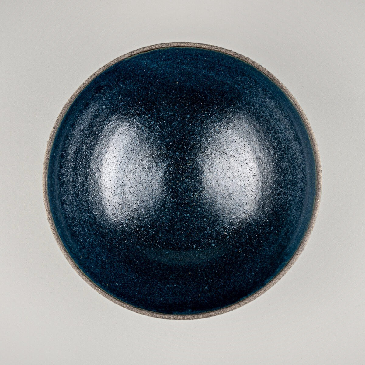 Top-down view of handmade ceramic bowl showing deep matte blue glazed interior.