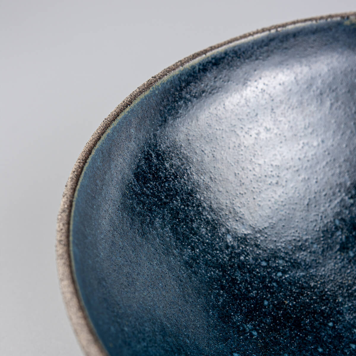 Close-up of interior surface texture and rich glaze variation in handmade stoneware bowl.