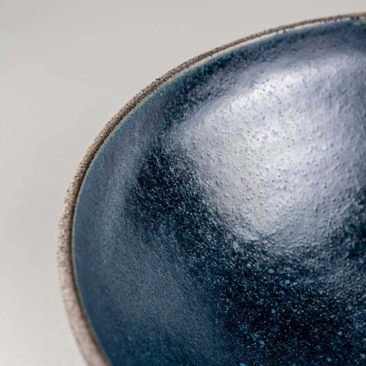 Close-up of interior surface texture and rich glaze variation in handmade stoneware bowl.