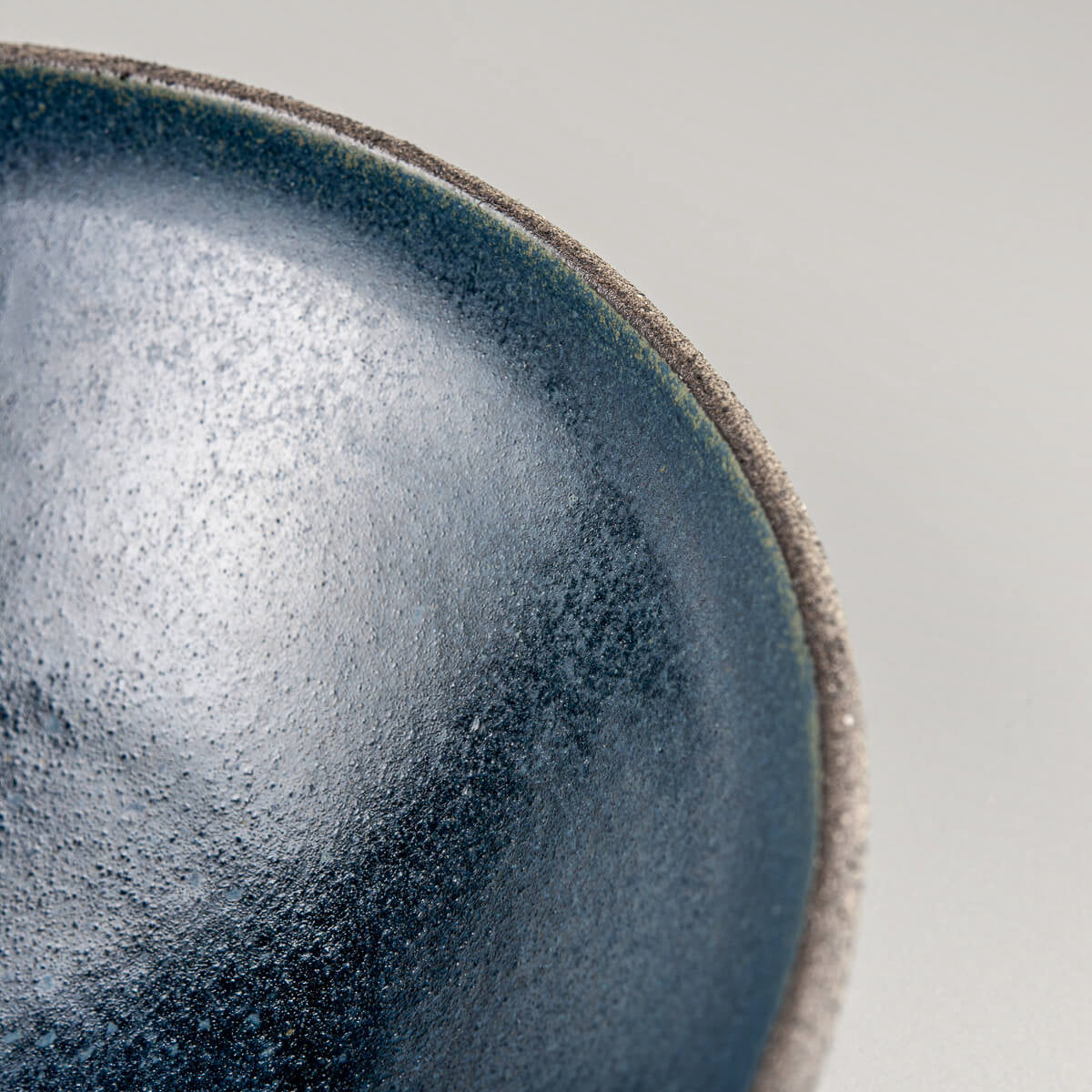 Natural stoneware texture on exterior surface of handmade bowl for kitchenware and decor.