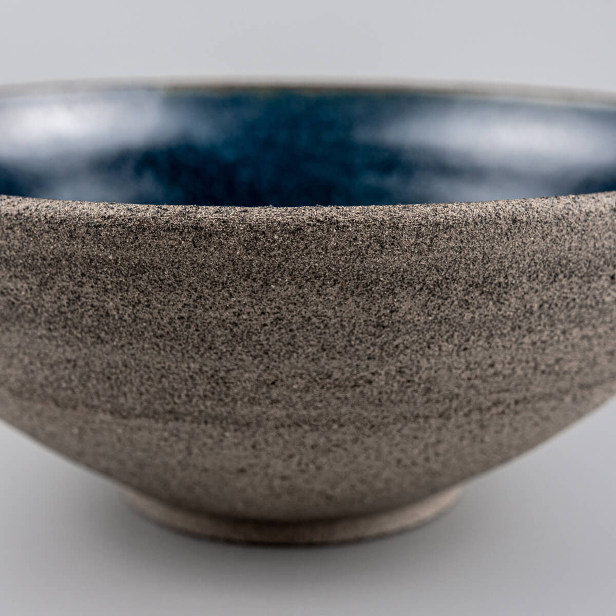 Underside detail of handmade ceramic bowl with artist’s mark and foot ring.
