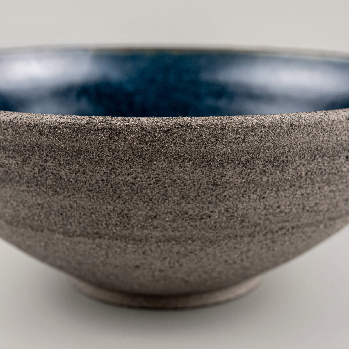 Underside detail of handmade ceramic bowl with artist’s mark and foot ring.