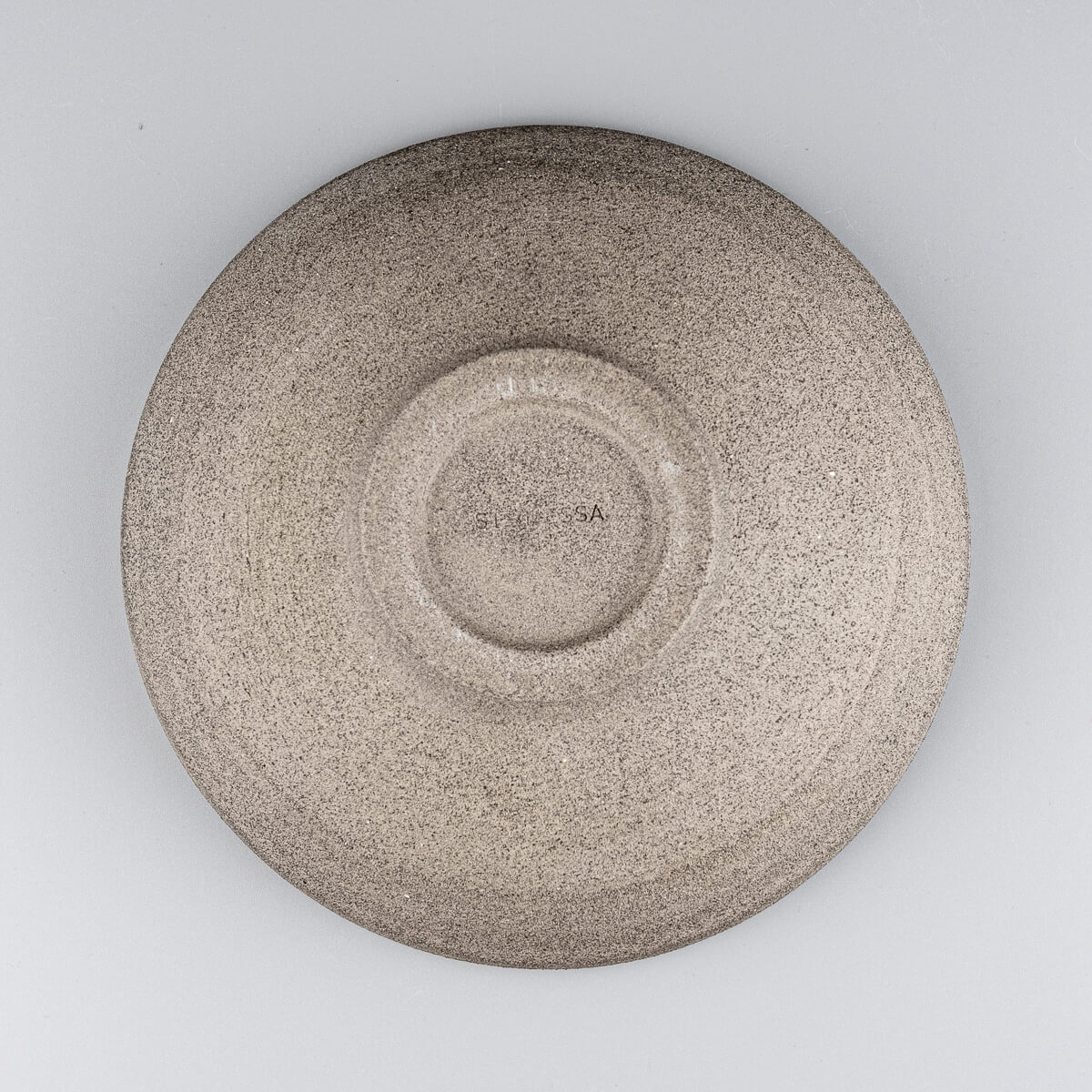 Underside detail of handmade ceramic bowl with artist’s mark and foot ring.