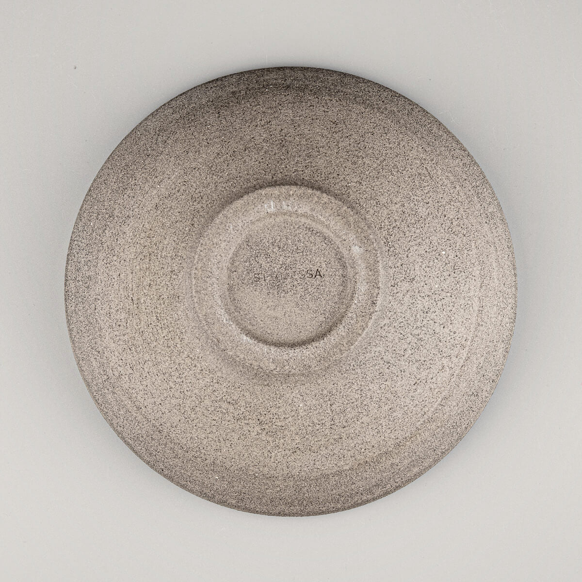 Underside detail of handmade ceramic bowl with artist’s mark and foot ring.