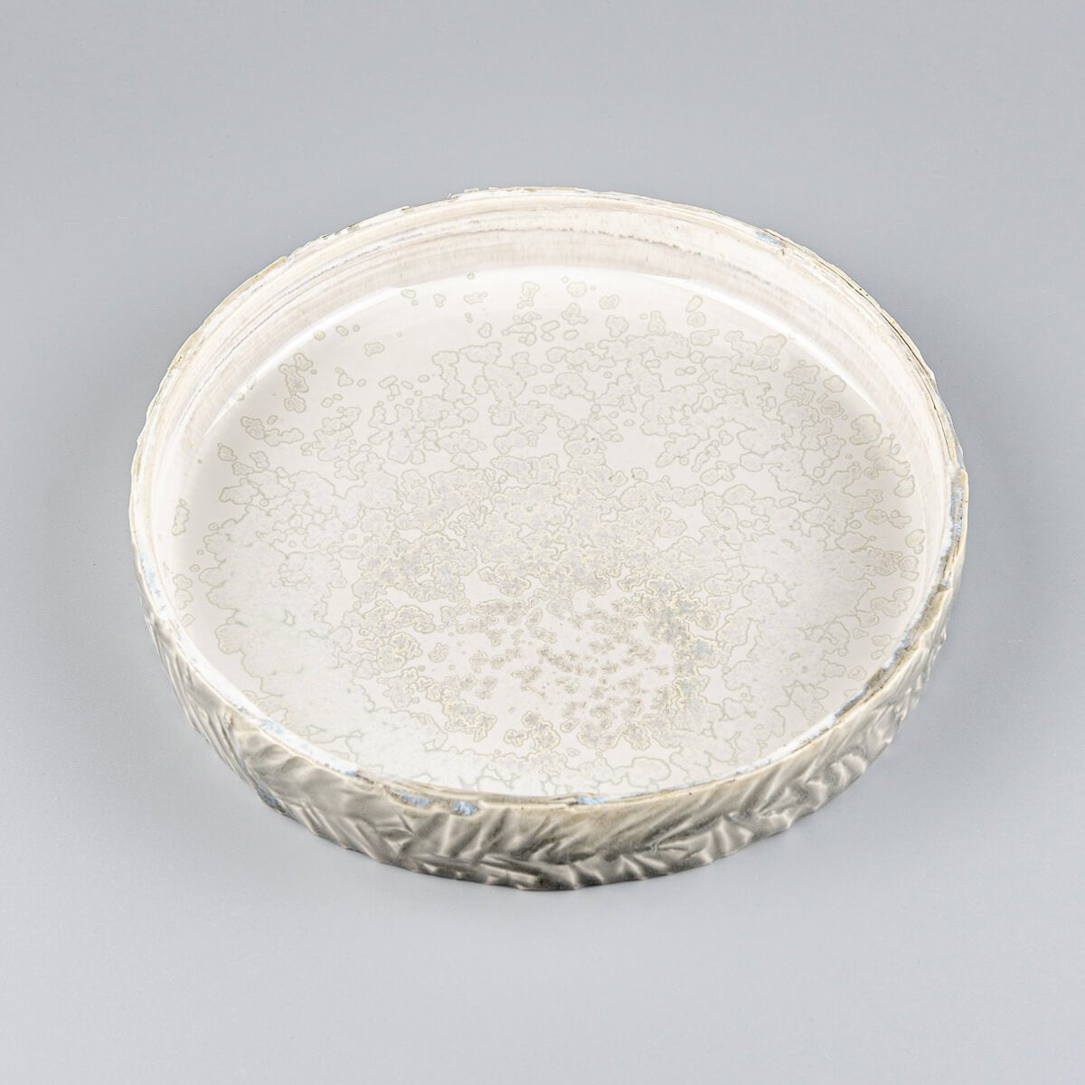Side view of unique ceramic plate highlighting glossy gray glaze and precise edge detailing.