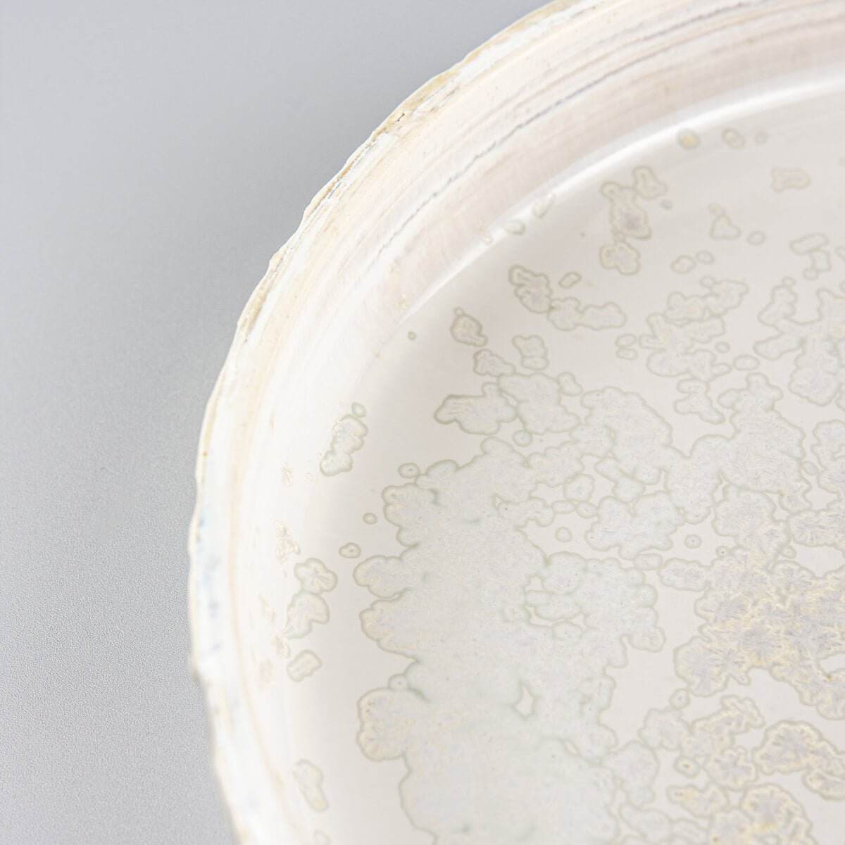 Interior view of artisan plate showing complementary soft gray glaze for luxury table settings.