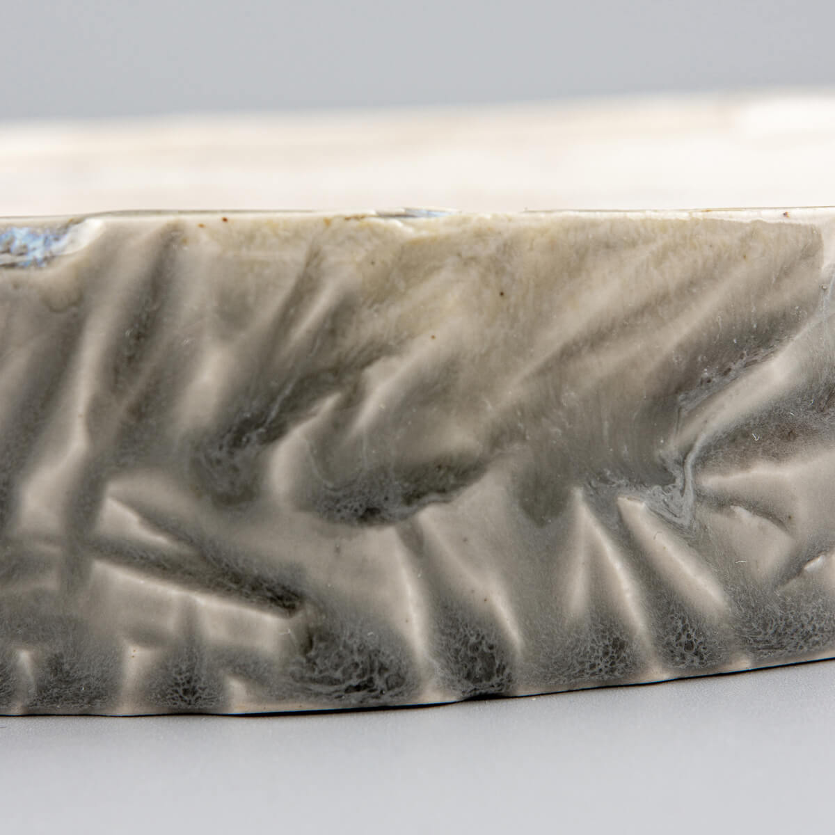 Detailed texture of carved stoneware edges on a unique ceramic plate for premium dining experiences.