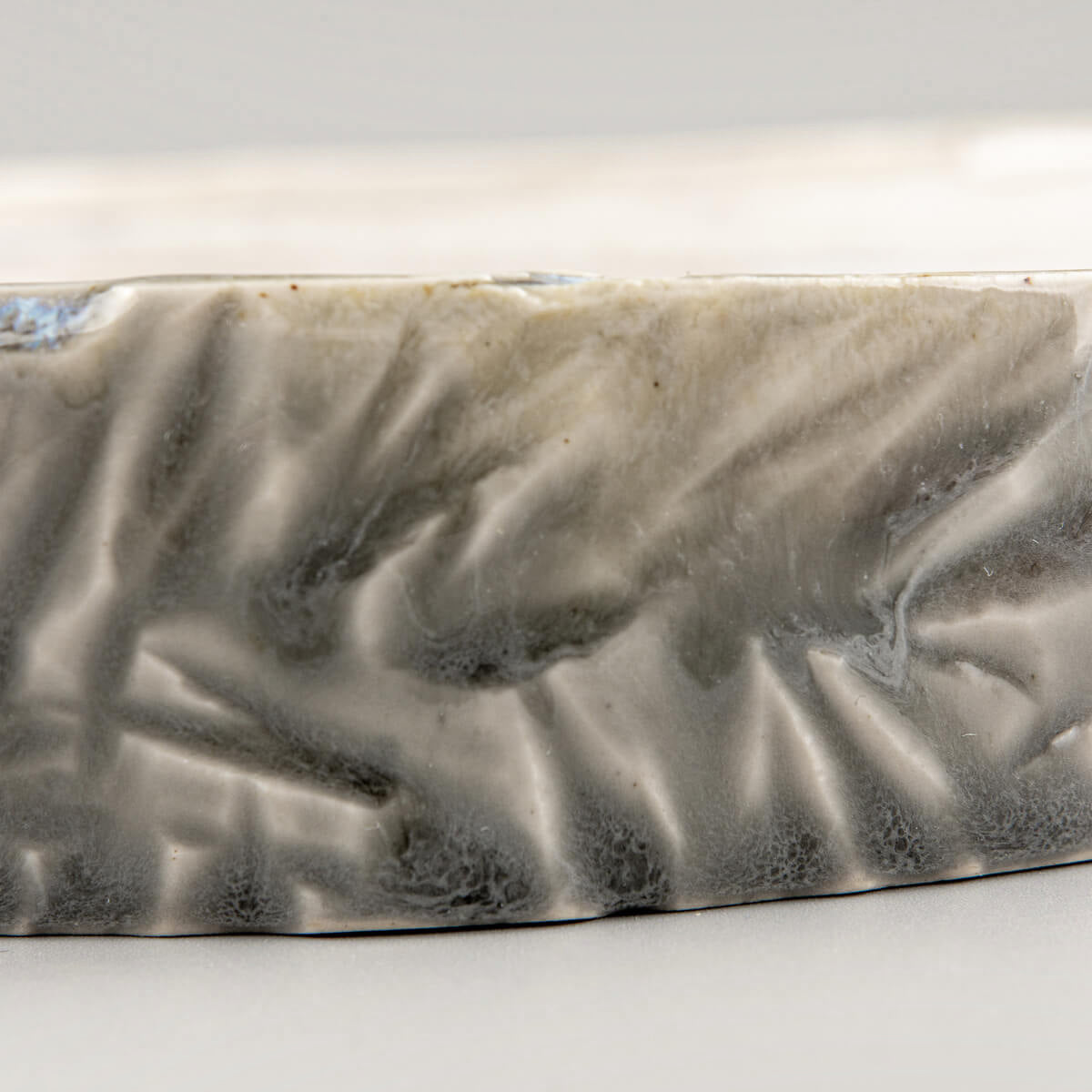 Detailed texture of carved stoneware edges on a unique ceramic plate for premium dining experiences.