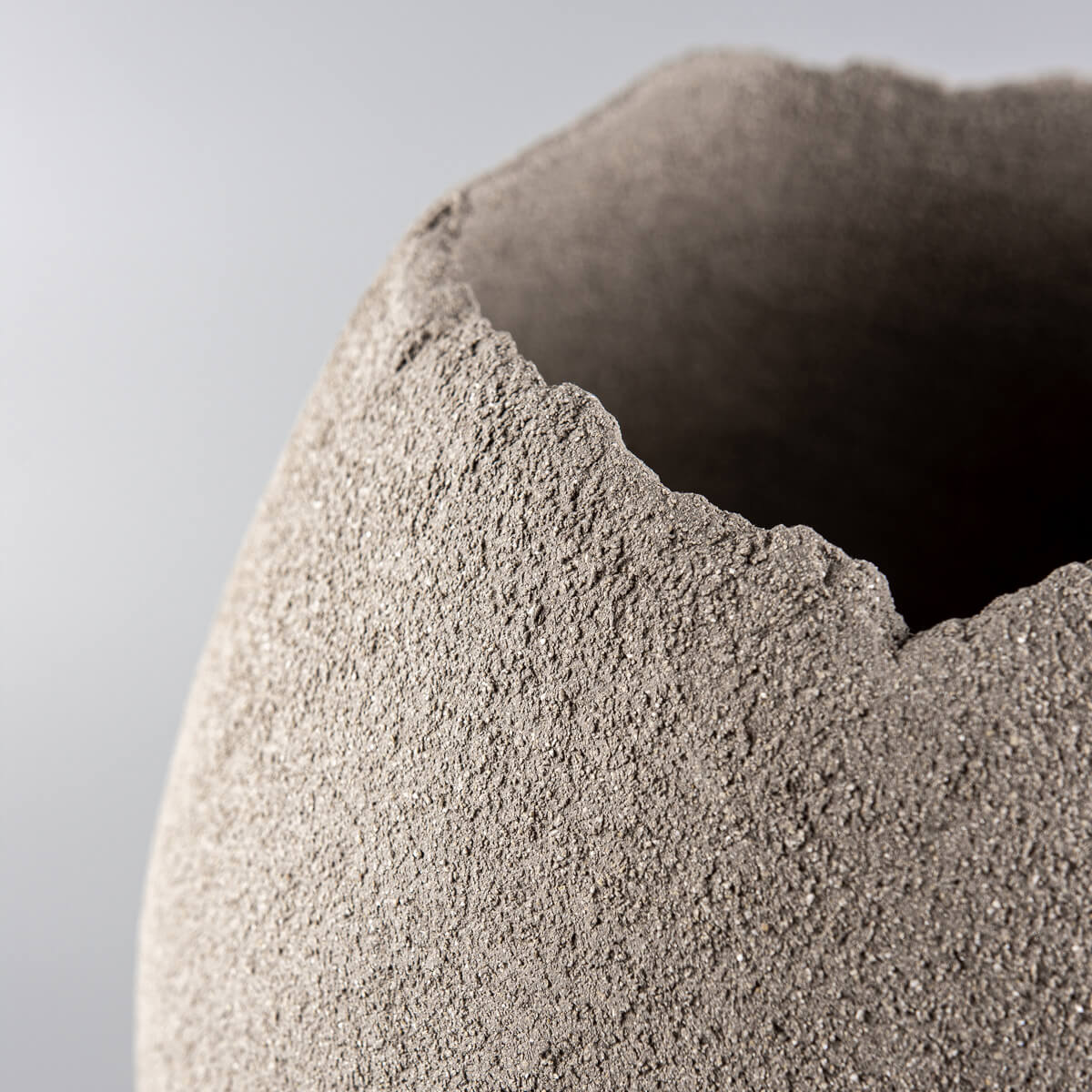 Close-up of handmade vases with a raw textured rim and sculptural design.