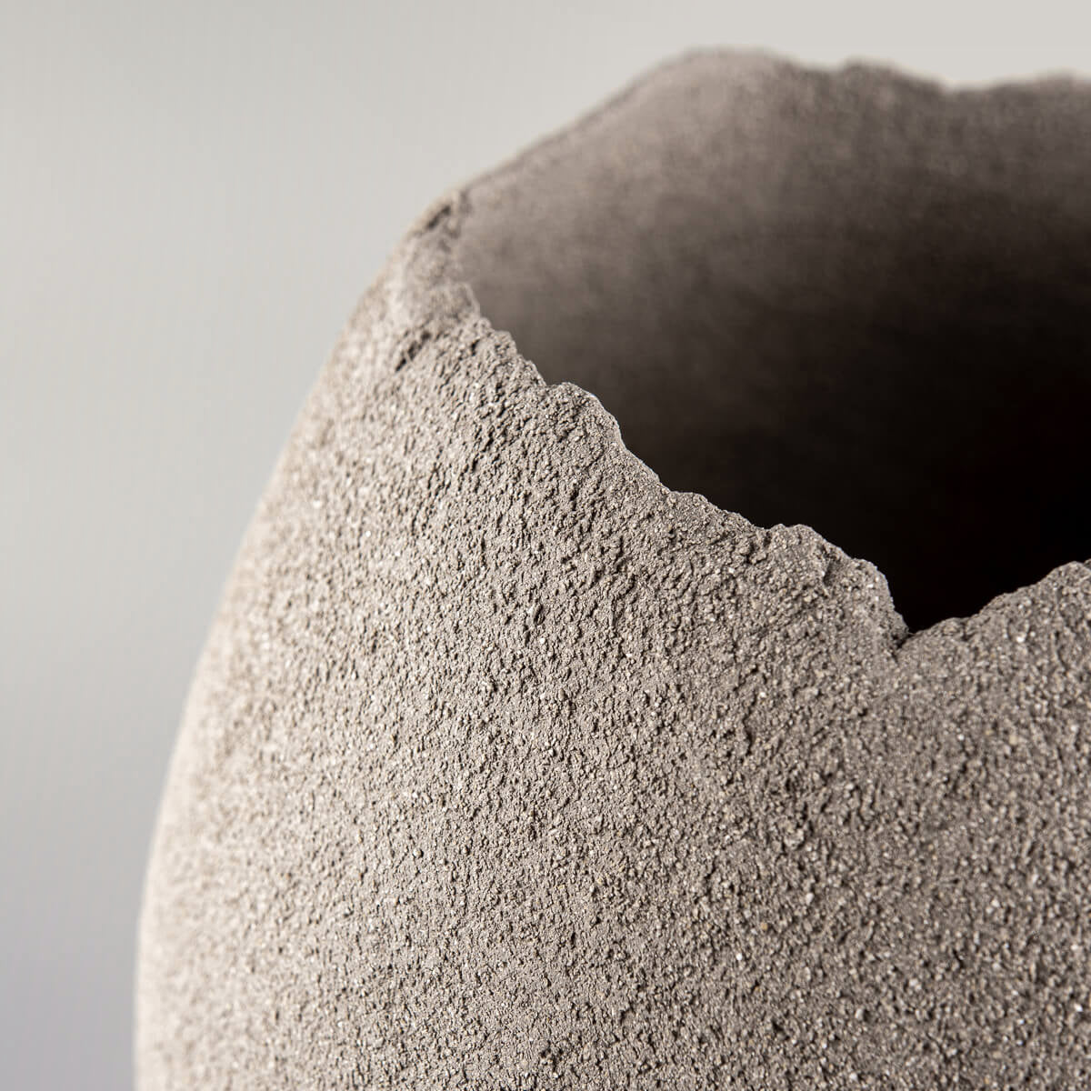Close-up of handmade vases with a raw textured rim and sculptural design.
