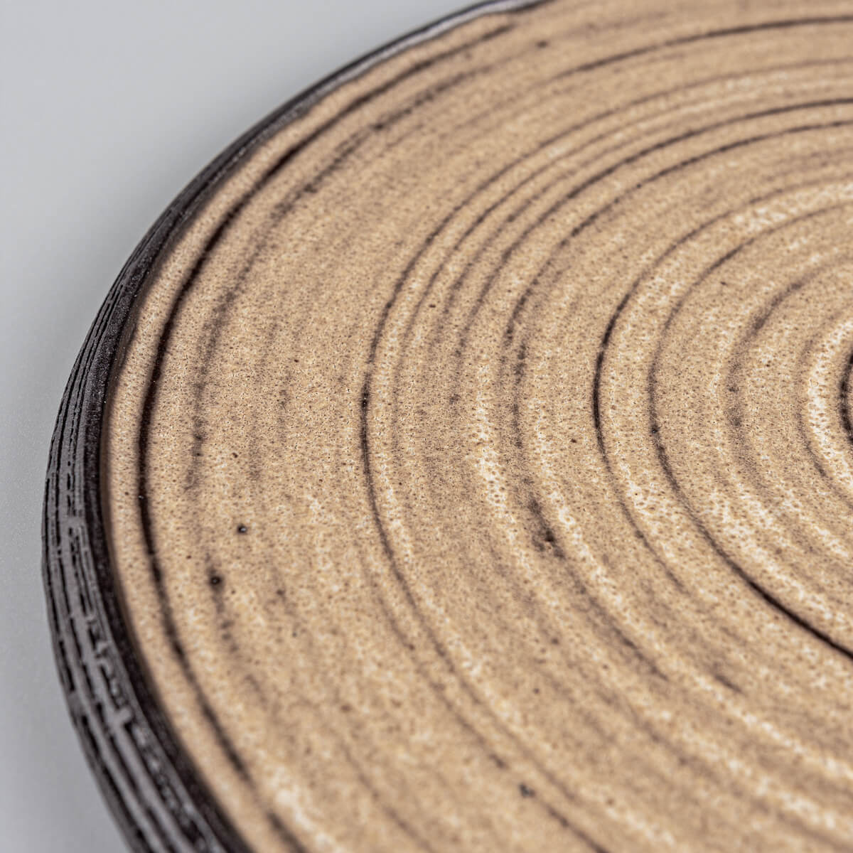 Detail view of matte ocher glazed handmade plate with fine carved rim.