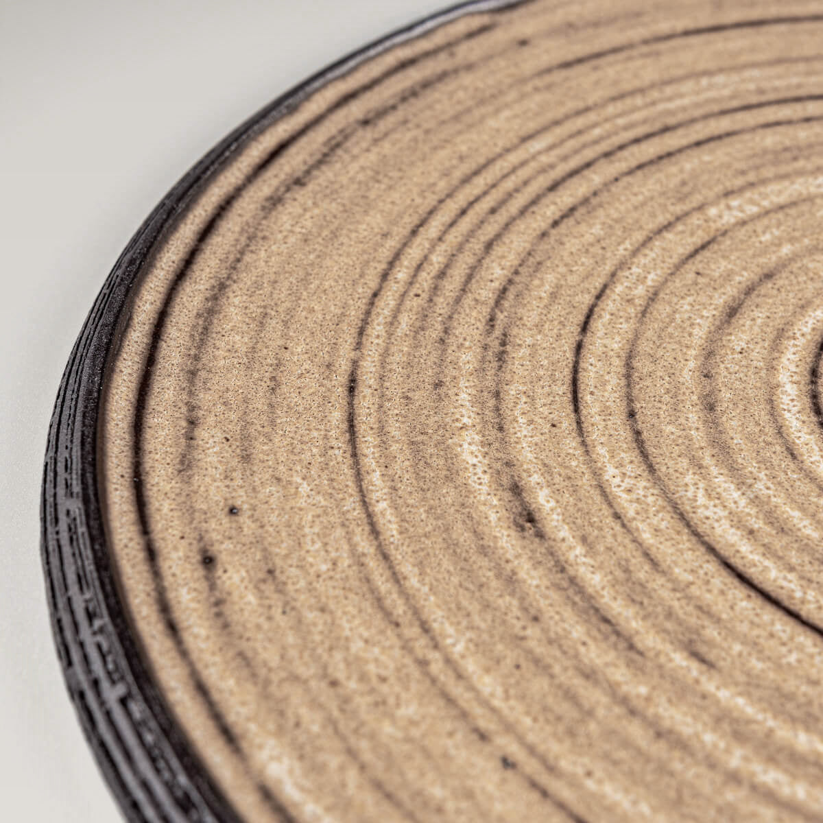 Detail view of matte ocher glazed handmade plate with fine carved rim.