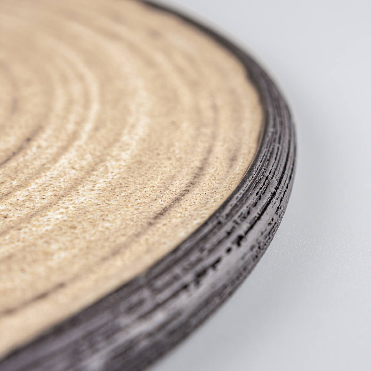 Fine dining ceramic plate with ocher finish and carved black stoneware edge.