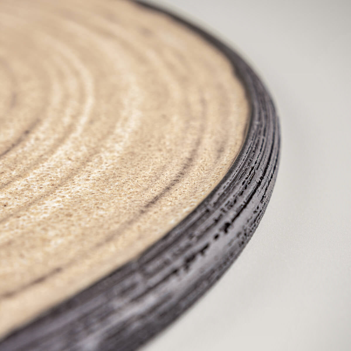 Fine dining ceramic plate with ocher finish and carved black stoneware edge.