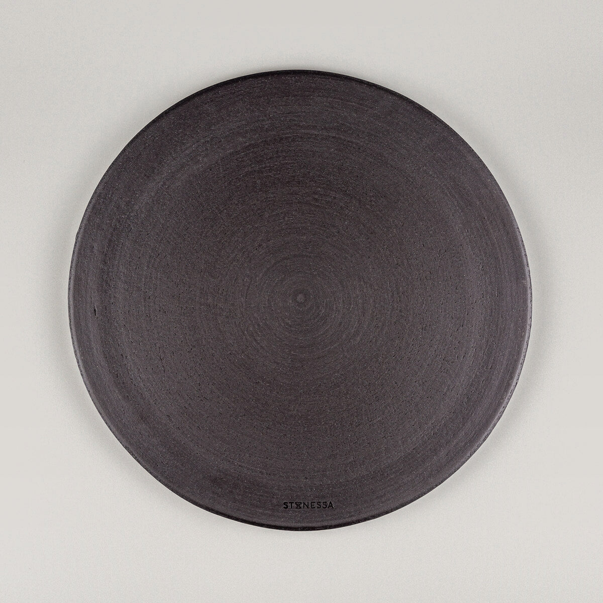 Bottom view of handmade ceramic plate in unglazed black stoneware.