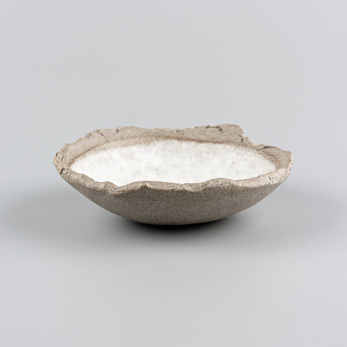 Side view of artisanal stoneware sushi plate with raw clay exterior and oval form.