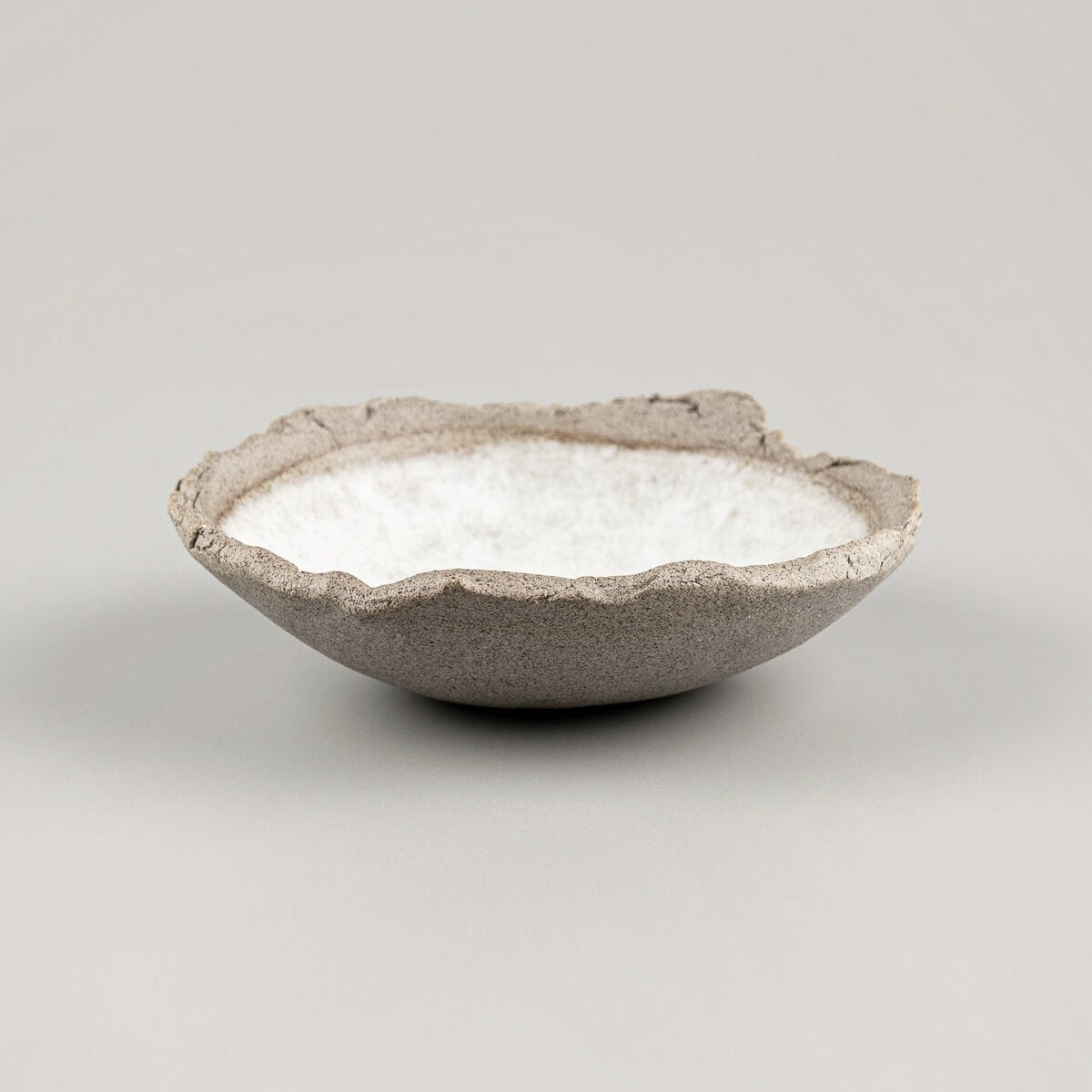 Side view of artisanal stoneware sushi plate with raw clay exterior and oval form.