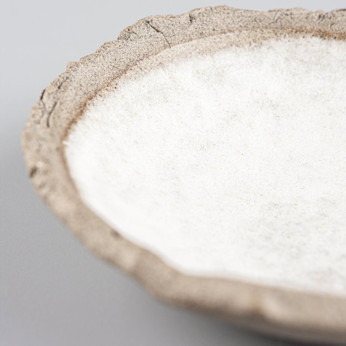 Angled view of handmade stoneware sushi plate with uneven rim.