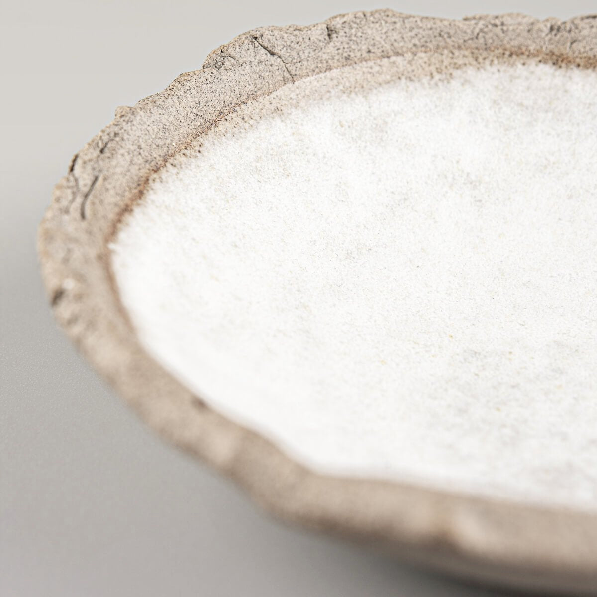 Angled view of handmade stoneware sushi plate with uneven rim.