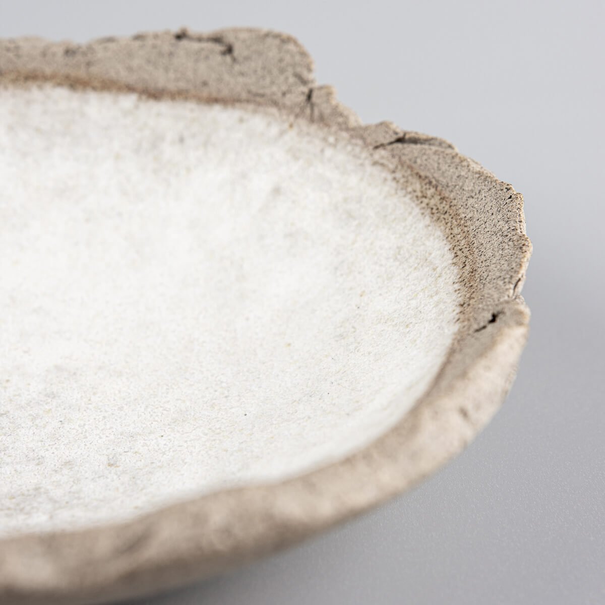 Close-up of textured stoneware rim and matte white glazed interior.