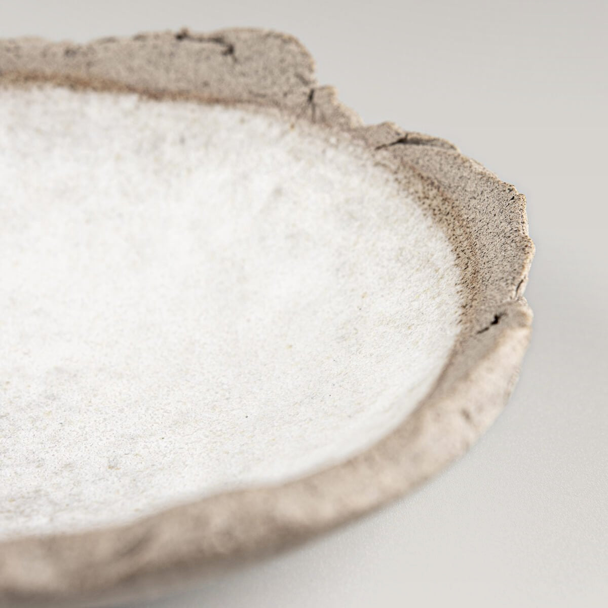 Close-up of textured stoneware rim and matte white glazed interior.