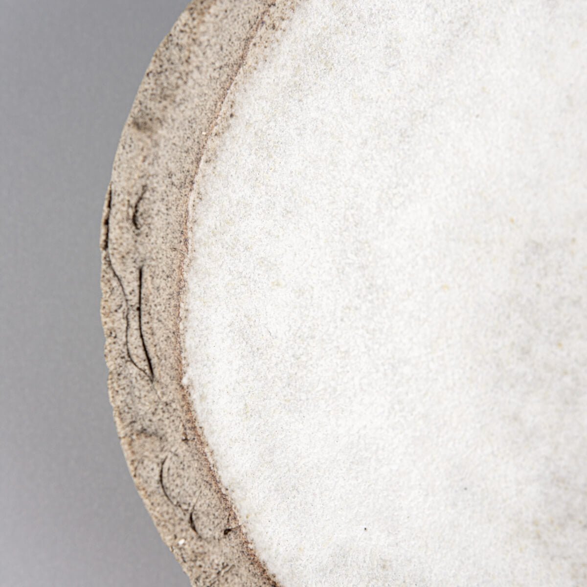 Detail of artisanal stoneware plate showing clay texture and glaze contrast.