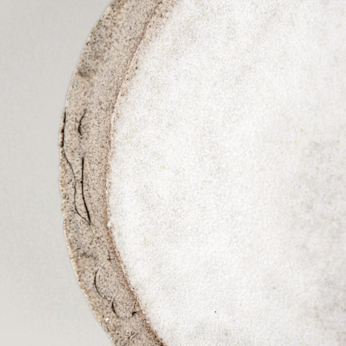 Detail of artisanal stoneware plate showing clay texture and glaze contrast.