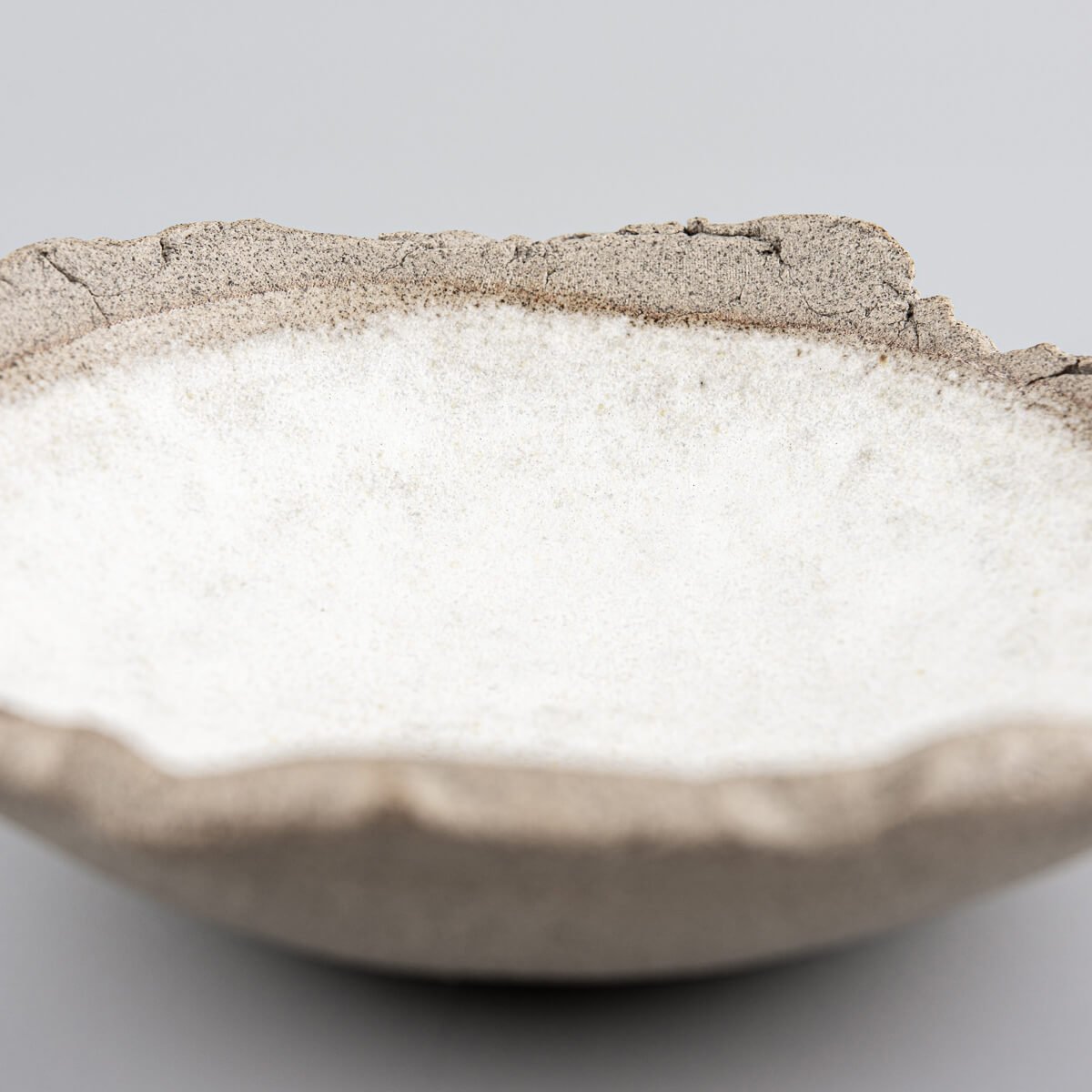 Profile view of a small handcrafted stoneware sushi plate with elevated edges.