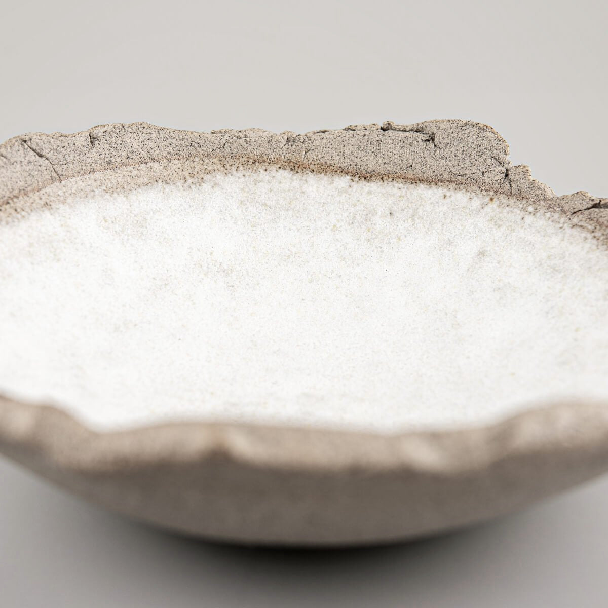 Profile view of a small handcrafted stoneware sushi plate with elevated edges.