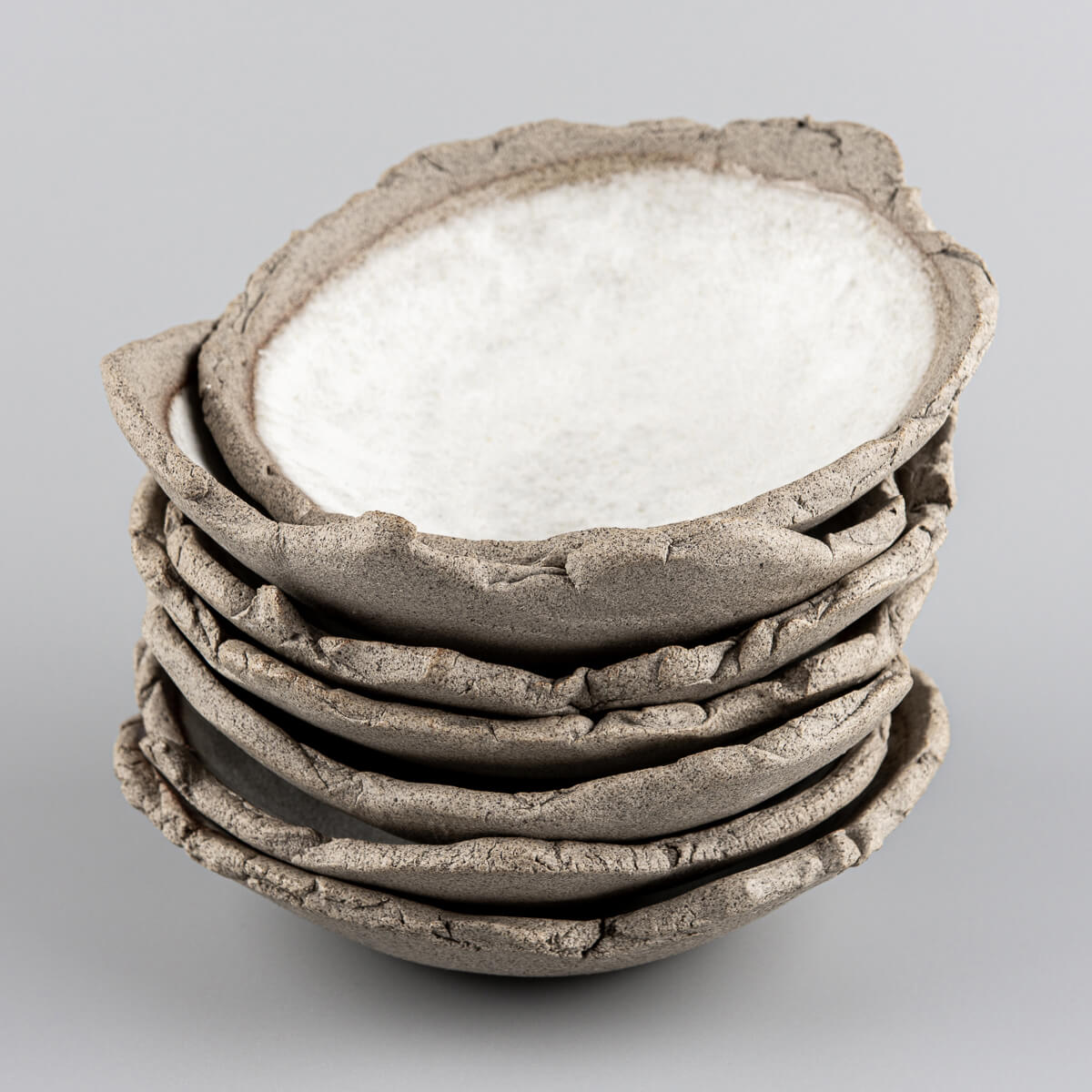 A stack of handmade stoneware sushi plates with organic textured rims.