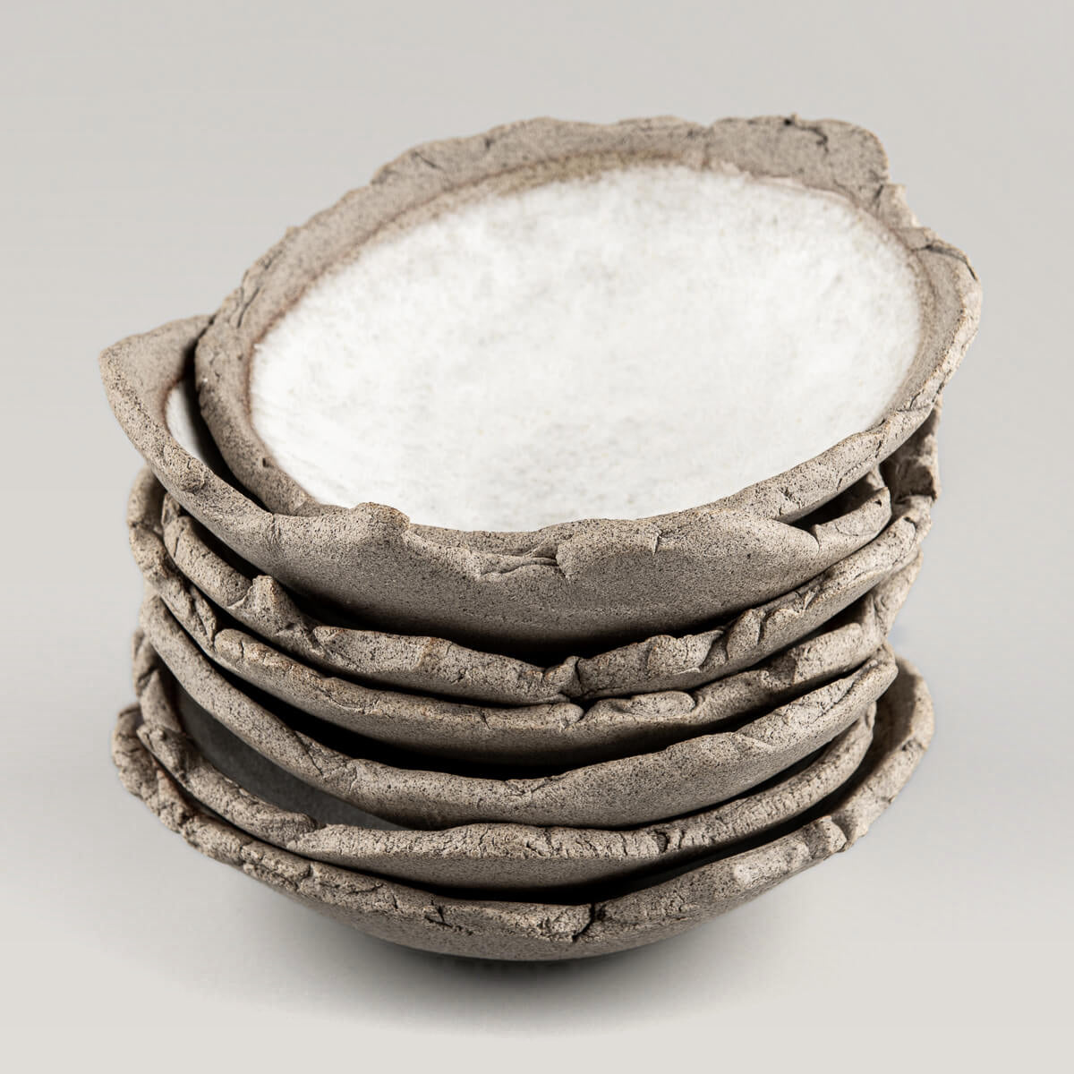 A stack of handmade stoneware sushi plates with organic textured rims.