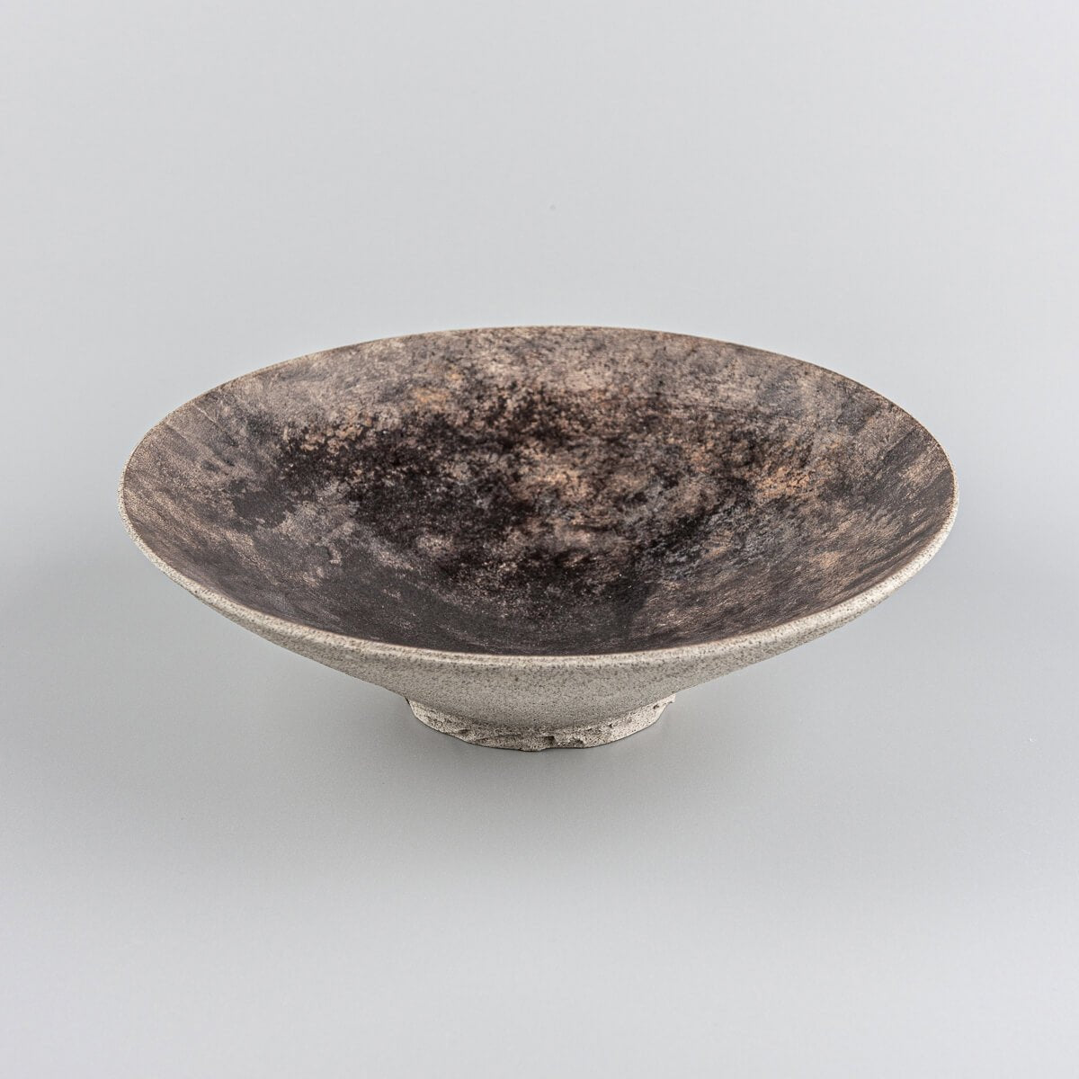 Rustic artisan stoneware plate showcasing unique glazing and natural clay finish.