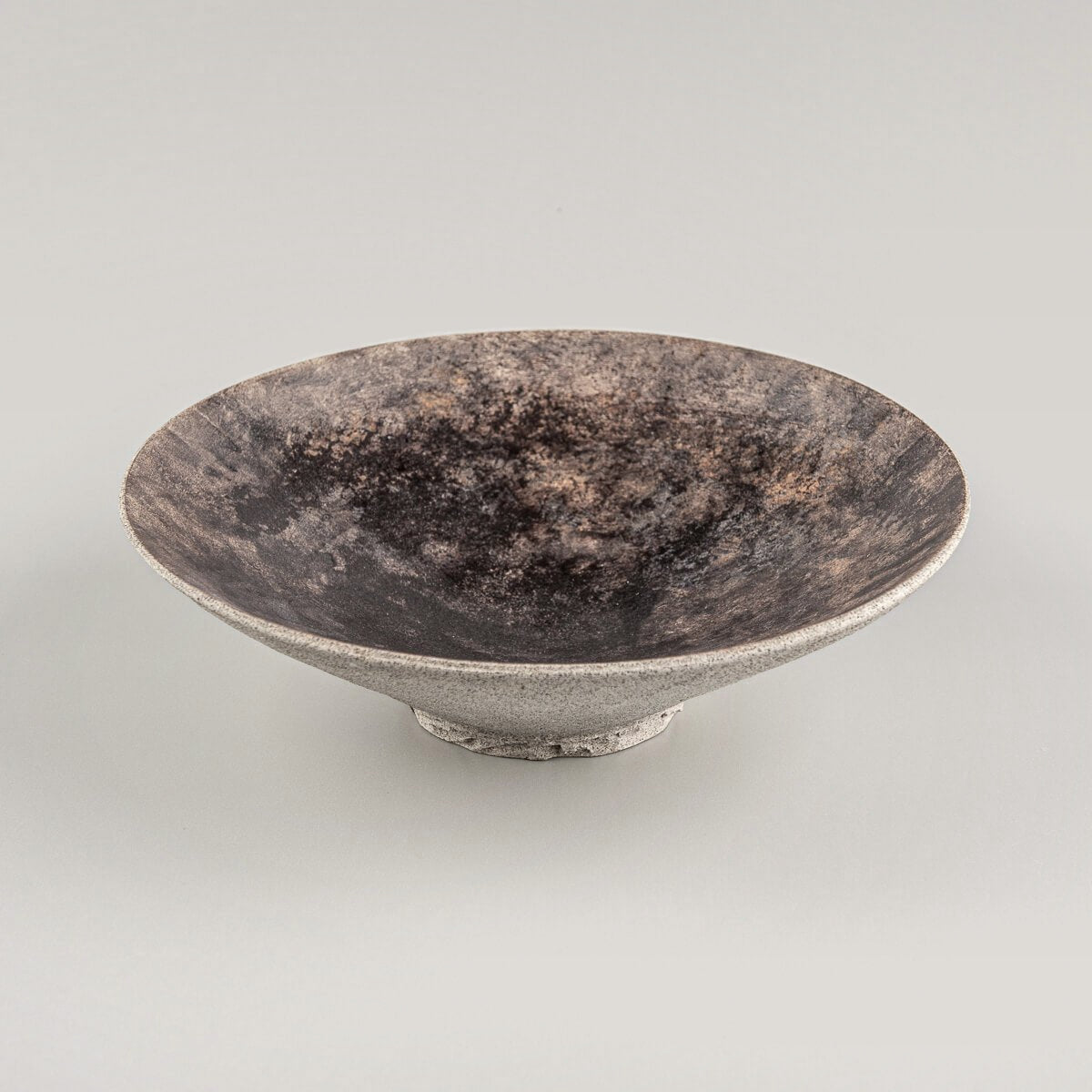 Rustic artisan stoneware plate showcasing unique glazing and natural clay finish.