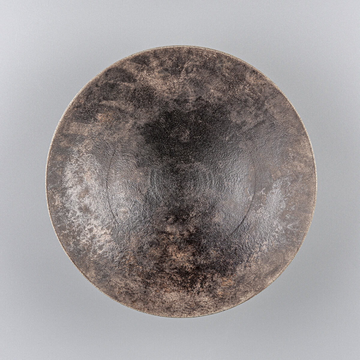 Elegant artisan stoneware plate with hand-carved base and glazed interior for fine dining.