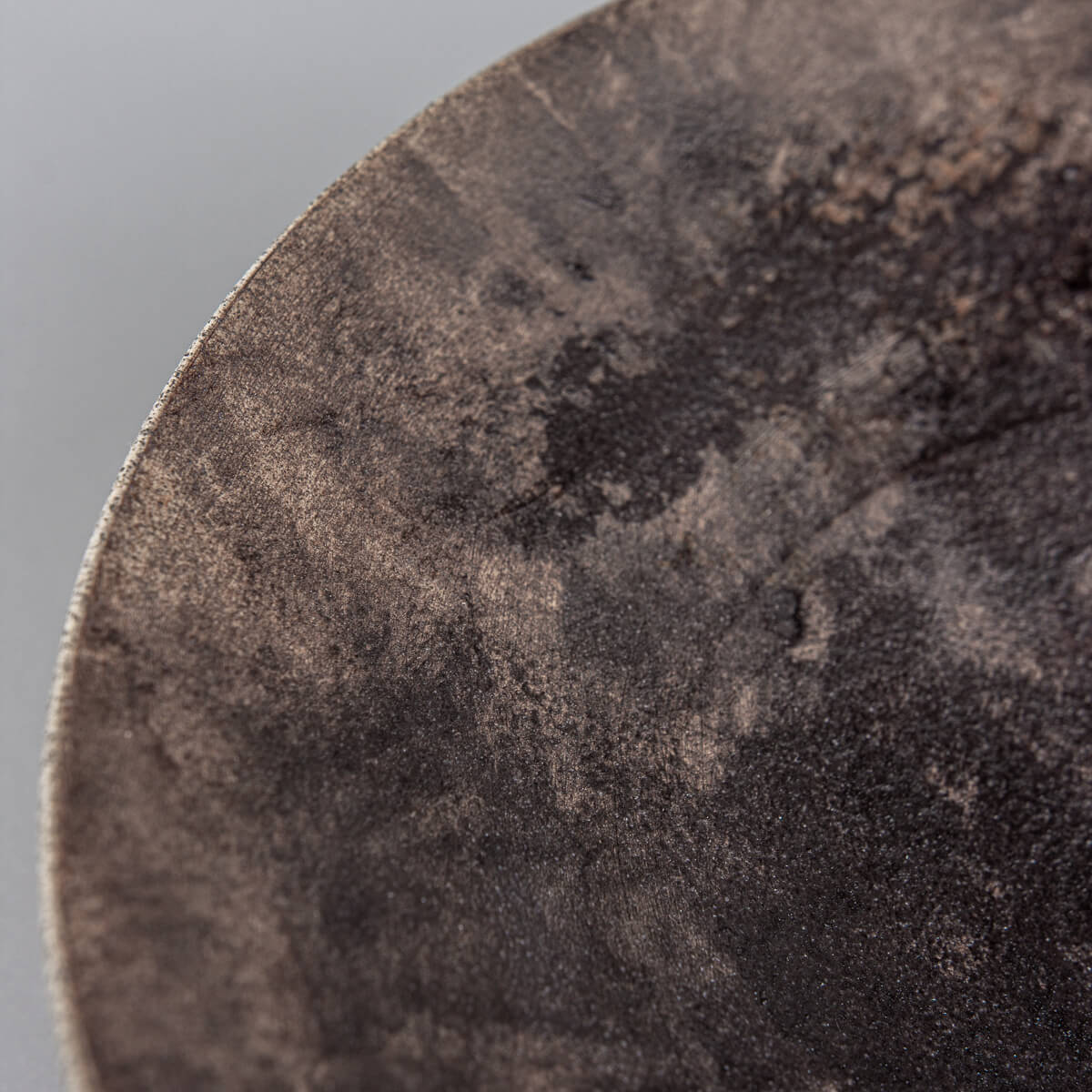 Close-up detail of artisan stoneware plate showing unique glaze texture and earthy tones.