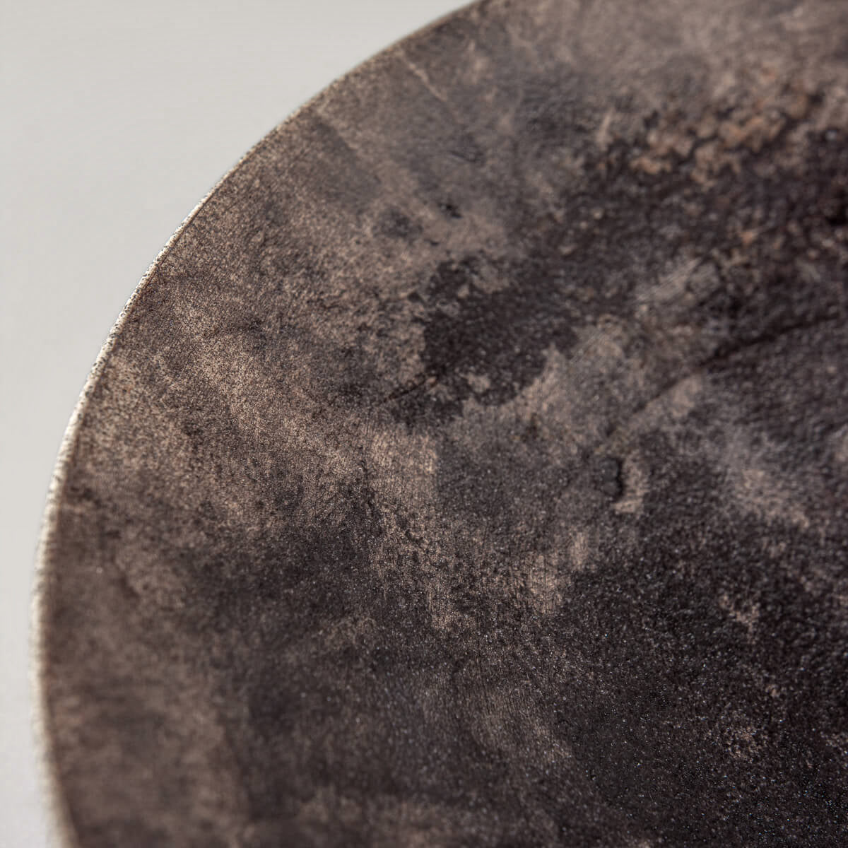 Close-up detail of artisan stoneware plate showing unique glaze texture and earthy tones.