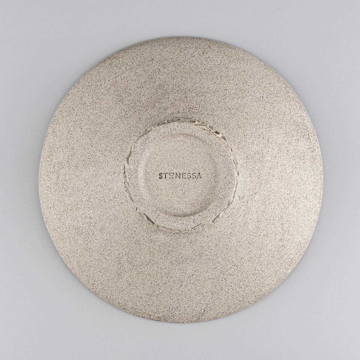 Underside of artisan stoneware plate showing carved base and raw clay finish.