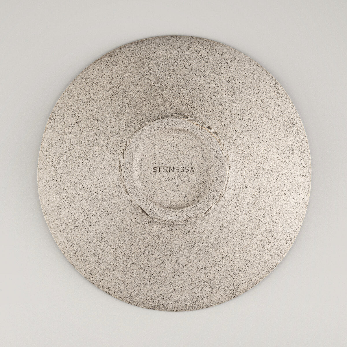 Underside of artisan stoneware plate showing carved base and raw clay finish.