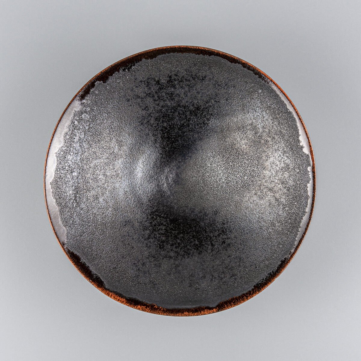 Handcrafted artisanal ceramic plate with black matte glaze interior and warm orange rim for luxury dining.
