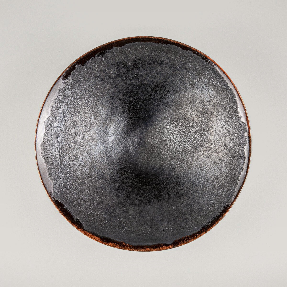 Handcrafted artisanal ceramic plate with black matte glaze interior and warm orange rim for luxury dining.