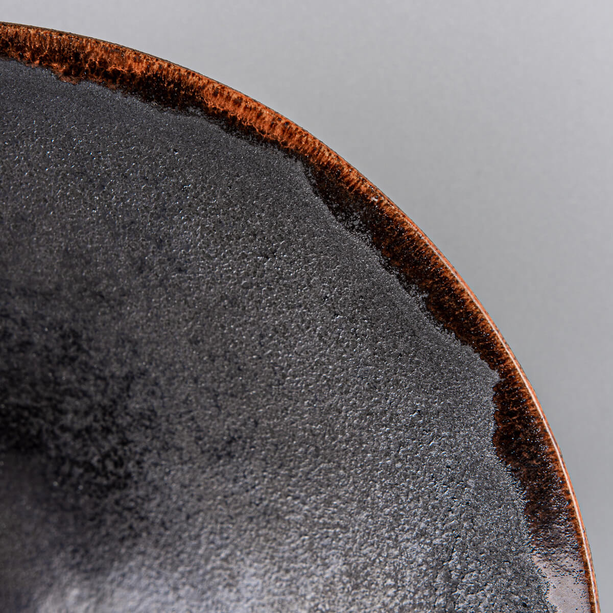 Close-up of textured ceramic plate rim with warm orange semi-transparent glaze.