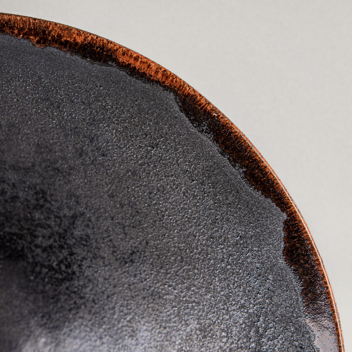 Close-up of textured ceramic plate rim with warm orange semi-transparent glaze.