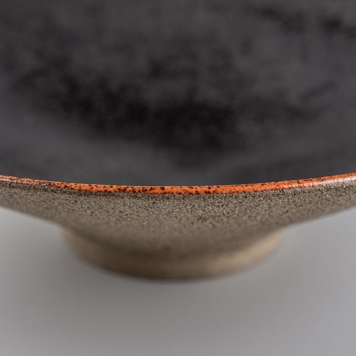 Base view of artisanal ceramic plate with unglazed natural dark stoneware finish.