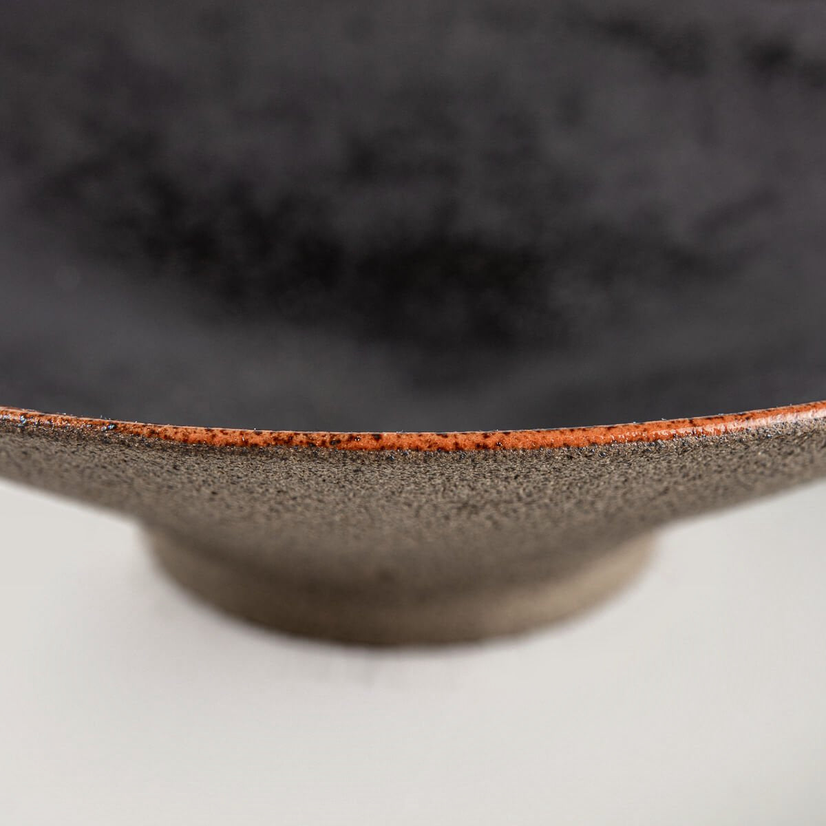 Base view of artisanal ceramic plate with unglazed natural dark stoneware finish.