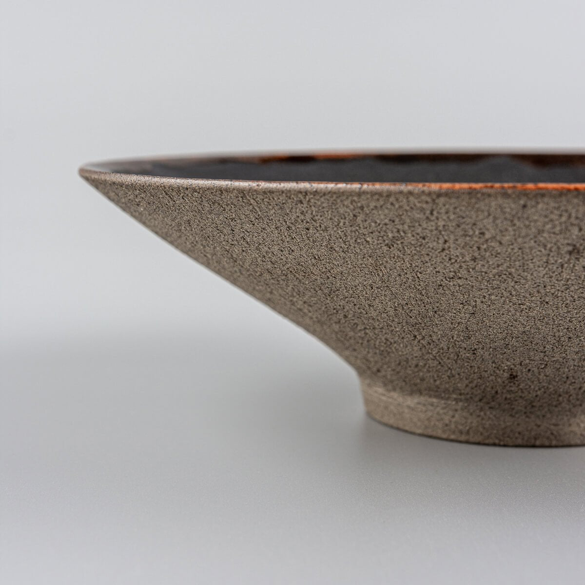 Profile view of artisanal ceramic plate showing elegant curve and elevated base.