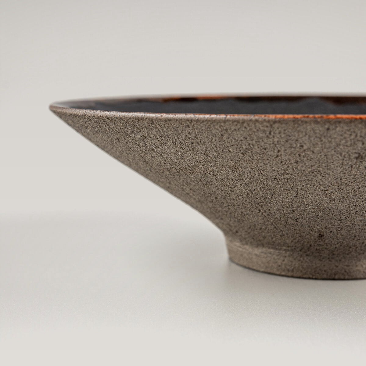 Profile view of artisanal ceramic plate showing elegant curve and elevated base.