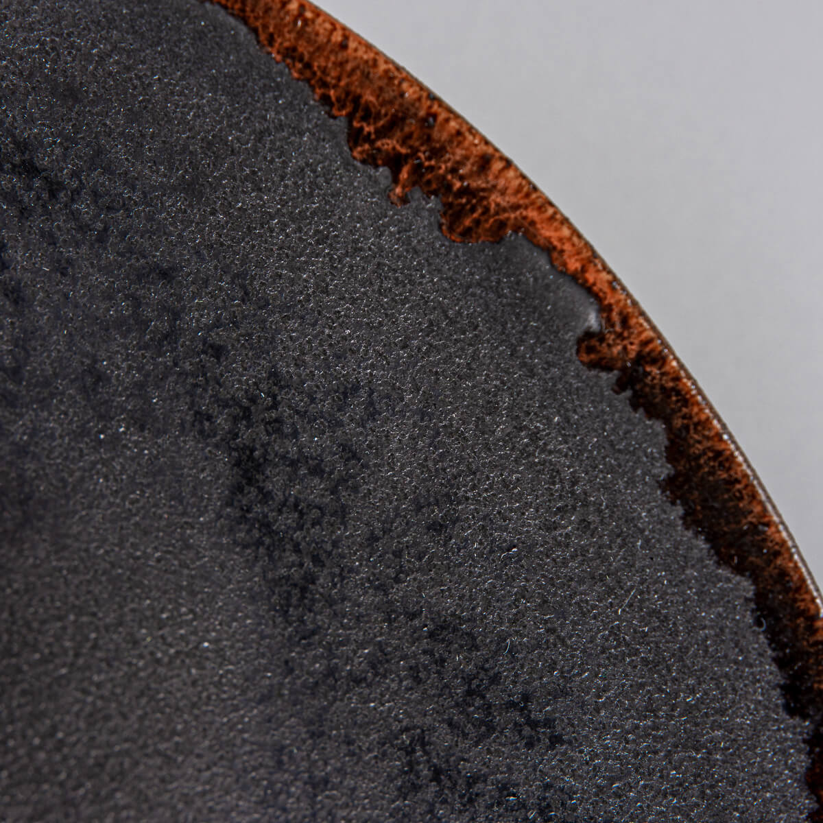 Detail of matte black glaze with subtle texture on artisanal ceramic plate.