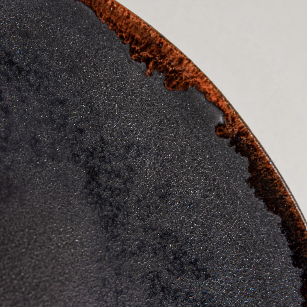 Detail of matte black glaze with subtle texture on artisanal ceramic plate.