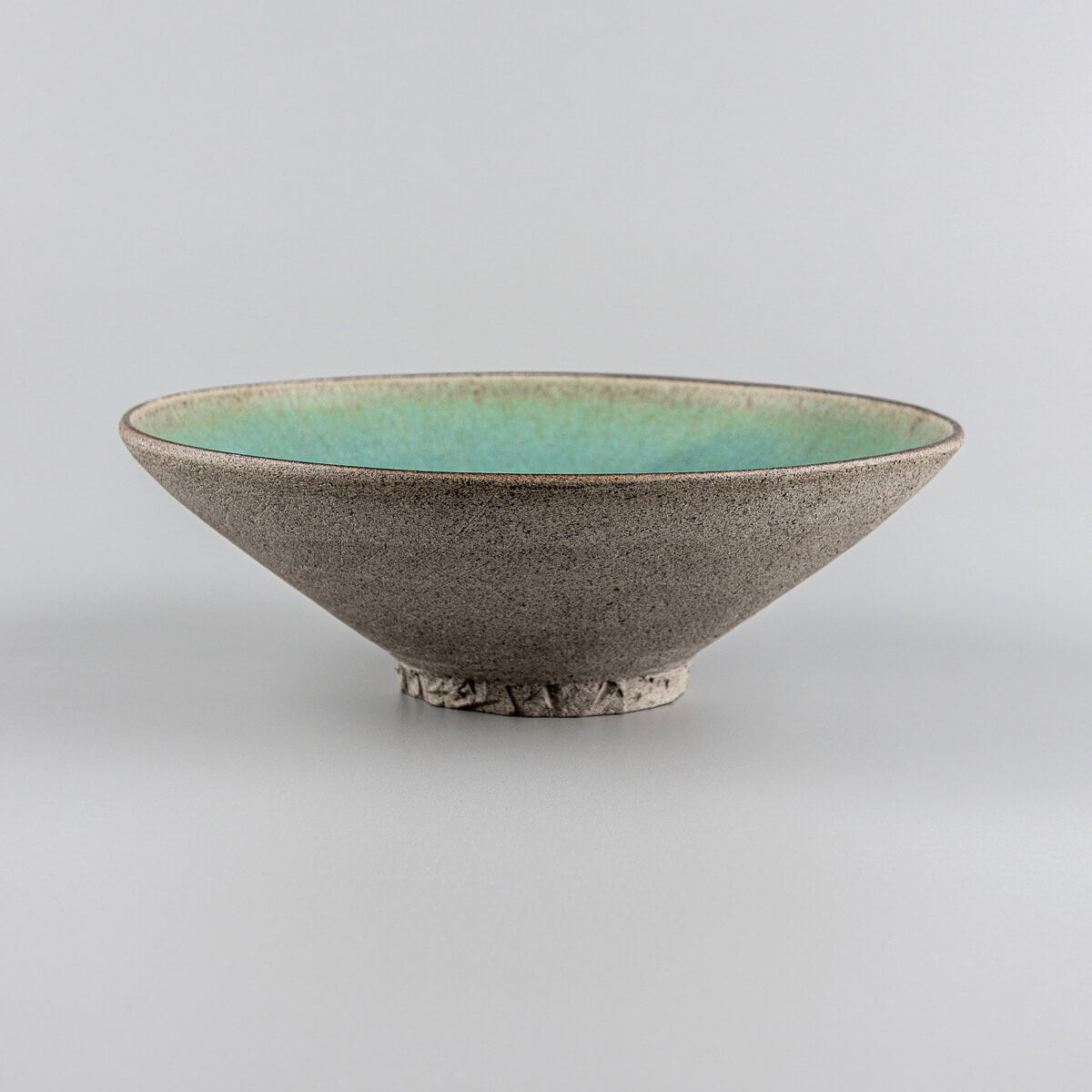 Side profile of artisanal ceramic plate with unglazed textured exterior.